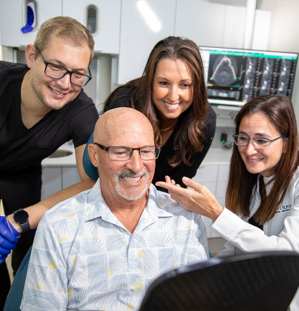 Doctor and her team all looking at patients new smile after dental procedure